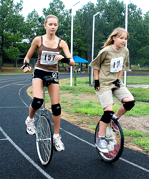 Two girls race close in unicycles
